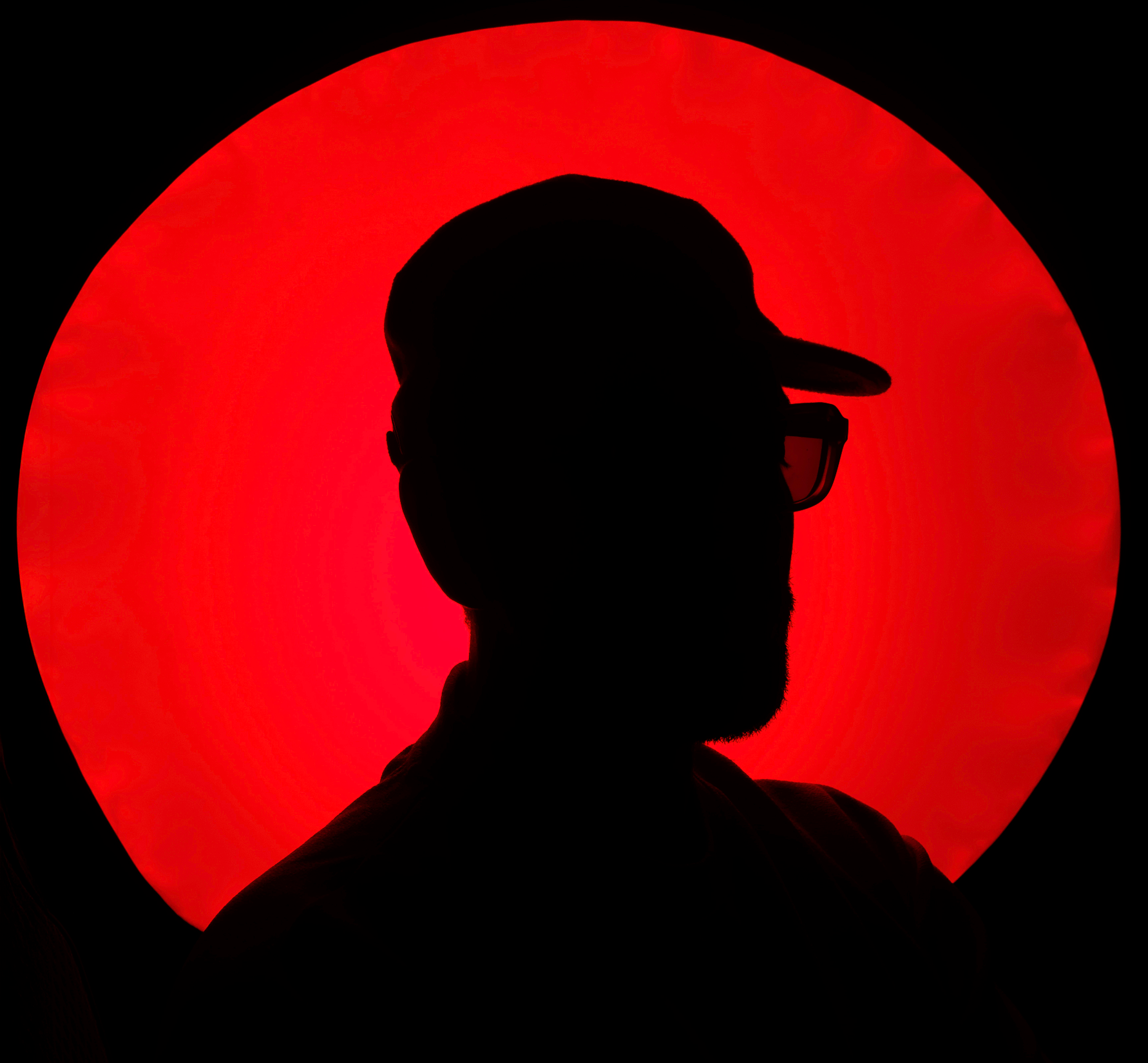 An artist in silhouette against a burnt red circle