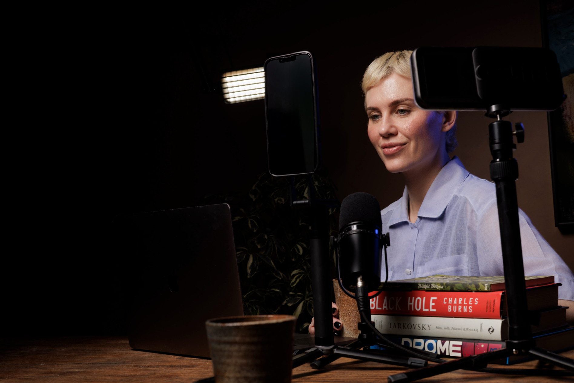 Lynda at a wooden desk with a microphone and phone-mounted SLITE.one