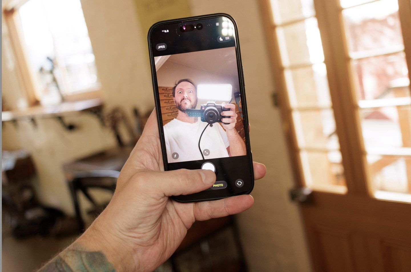 A creator filming himself on a phone held in his own hand, a camera in the shot
